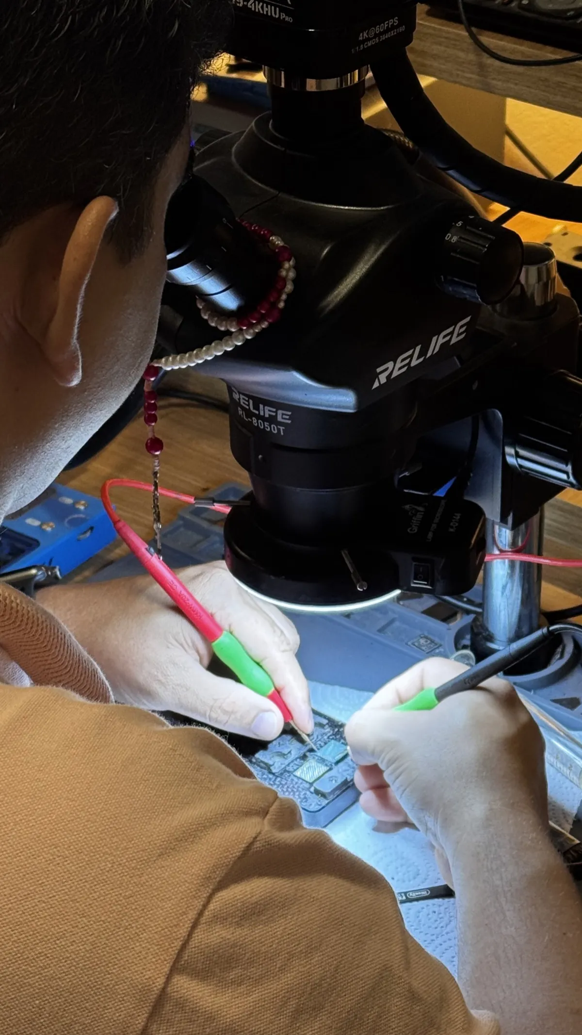 Técnico realizando microsoldagem em placa com microscópio profissional